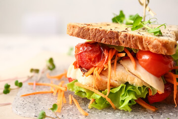 Board with tasty sandwich on light background, closeup