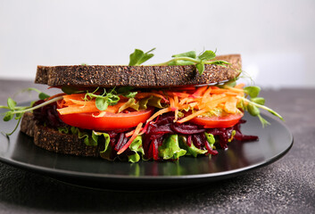Plate with tasty sandwich on dark table, closeup