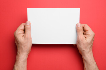 Man holding blank sheet of paper on color background, closeup
