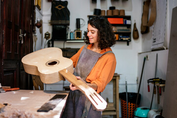 woman luthier making guitars in her musical instrument workshop