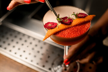 close-up of glass with frothy drink that barman accurate decorates with green twigs