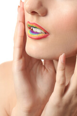 Beautiful young woman with rainbow lips on white background, closeup