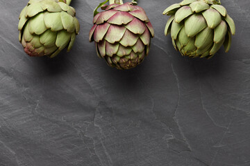 Obraz premium Fresh artichokes on dark gray stone background