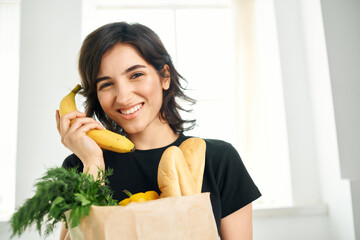 cheerful woman package with groceries in the kitchen healthy food homework