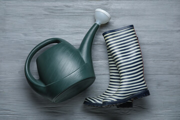 Watering can and gumboots on dark wooden background