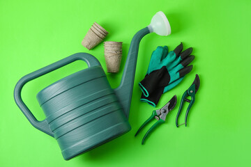 Watering can, peat pots, gloves and secateurs on color background
