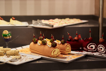 Naklejka na ściany i meble Caramel and chocolate rolls desserts with fruits for picking up from buffet for hotel system of all-inclusive. Copy space