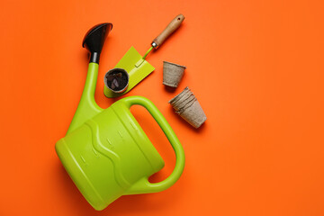 Watering can, peat pots and gardening shovel with soil on color background