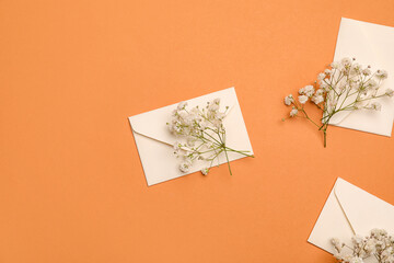 Beautiful gypsophila flowers and envelopes on color background