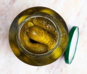 Glass jar with pickled cucumbers on a wooden table. High quality photo