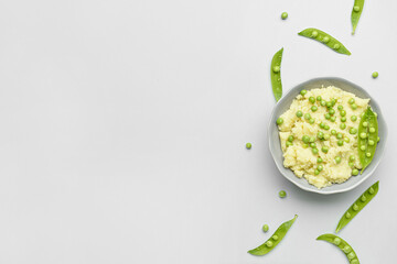 Bowl with mashed potatoes and green peas on grey background