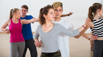 Group of satisfied teen learning to dancing tango in dance studio
