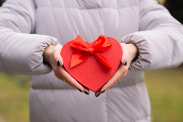 Female hands holding a heart shaped gift box