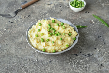 Bowl with mashed potatoes and green peas on grunge background
