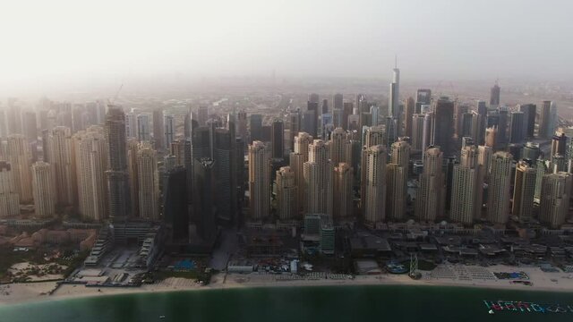 Vertical panning from a quadcopter. Aerial shot of beach and skyscrapers, Dubai.