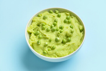 Bowl with mashed potatoes and green peas on color background