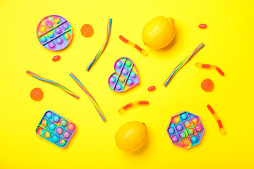 Pop it fidget toys, sweets and lemon on color background