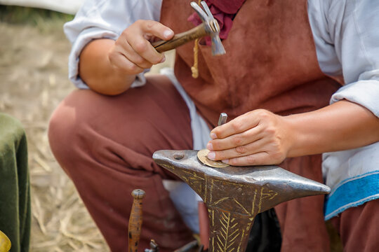 Close up image of the artist at work. He is carefully using a hammer made a decoration