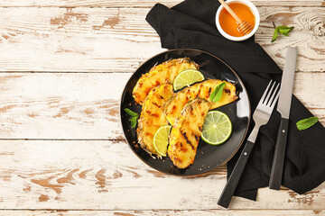 Plate with grilled pineapple slices and honey on light wooden background