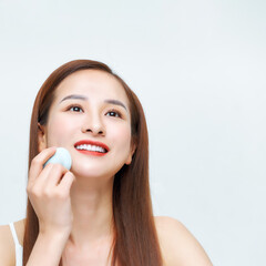 Young beautiful woman applying cosmetic with sponge