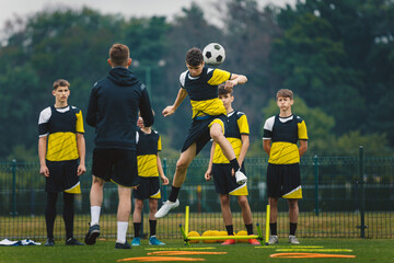 Teenage football players training headshots  Young player jumping high and head ball. Coach...