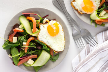 Fresh organic mesclun mix salad with cucumber, mozzarella and salmon, scrambled eggs, delicious hearty breakfast