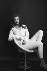 Glamorous model sitting on a chair at dark room
