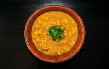 Arabic cuisine - plain peeled fava beans in a white bowl on a dark brown background. Top view. Foul Mudammas