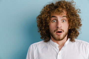 Fototapeta na wymiar Young curly man with ginger hair expressing surprise at camera