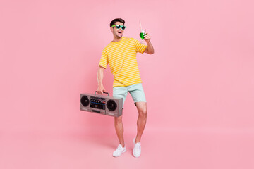 Full body photo of cheerful young happy man hold hand boombox cocktail look empty space isolated on...