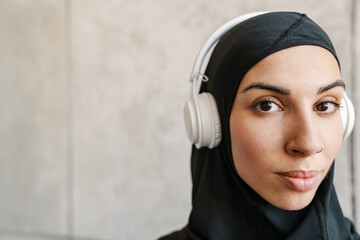 Young muslim sportswoman in hijab listening music with headphones