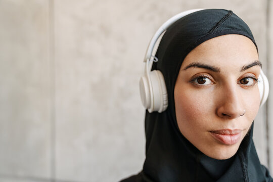 Young muslim sportswoman in hijab listening music with headphones