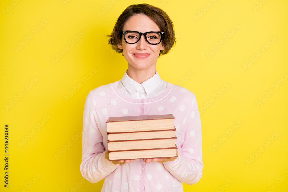 Poster Photo portrait of female geek studying keeping book pile smiling isolated vivid yellow color background