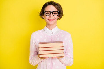 Photo portrait of female geek studying keeping book pile smiling isolated vivid yellow color...