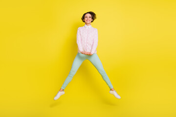 Fototapeta na wymiar Full length body size photo of cheerful playful girl jumping high isolated vivid yellow color background