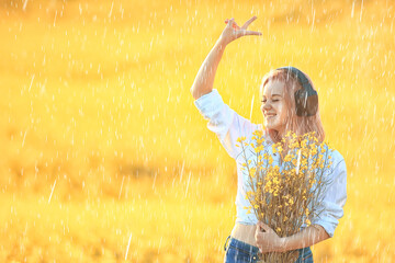 girl with headphones listening to music in summer rain outside summertime music - obrazy, fototapety, plakaty