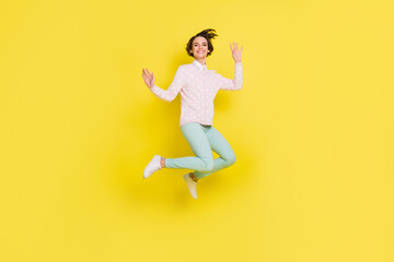 Full length body size photo of cheerful model jumping up waving hands laughing isolated bright yellow color background