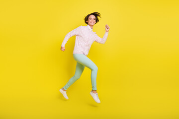 Fototapeta na wymiar Full length body size photo of cheerful model jumping high running fast smiling isolated vivid yellow color background