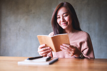 Obraz premium A beautiful young asian woman reading a book