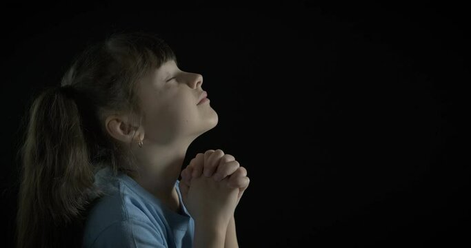 Wishful child pray. A calm wishful child sits in loneliness and pray in the room.