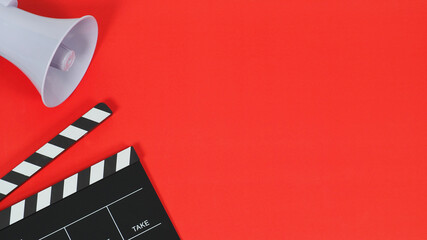 Clapperboard or movie slate and megaphone on red blackground.