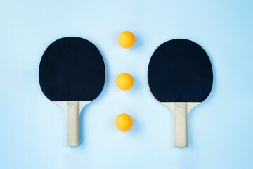 Two black ping pong paddles on light blue background