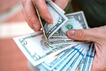 A man counts a stack of bills dollars, close up