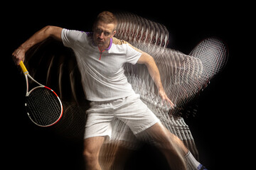 Power and speed. Young man, professional tennis player in motion and action isolated on dark...