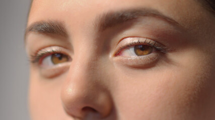 Fototapeta premium Young woman charming brown eyes with mascara. Look in the camera. Studio shot with dramatic light extreme close-up high quality photo portrait.