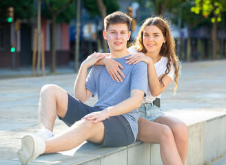 Girl is sitting with young man and hugging him from behind
