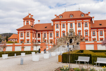 Prague, Czech Republic, 25 April 2021: Troja castle, Historical chateau and red and white baroque palace surrounded by a garden at spring day, staircase decorated with stone sculptures - obrazy, fototapety, plakaty