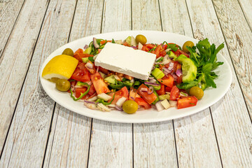 Mediterranean salad tray with fresh cheese, cucumber and chopped tomato, green olives, cucumbers and red onion and lemon with fresh parsley.