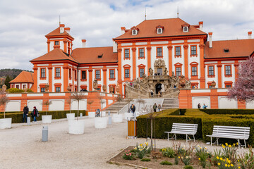 Prague, Czech Republic, 25 April 2021: Troja castle, Historical chateau and red and white baroque palace surrounded by a garden at spring day, staircase decorated with stone sculptures - obrazy, fototapety, plakaty