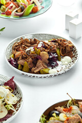 Beef tongue with pickles among other appetizers on a light table, assorted appetizers with beef tongue accent with pickles and red cabbage.